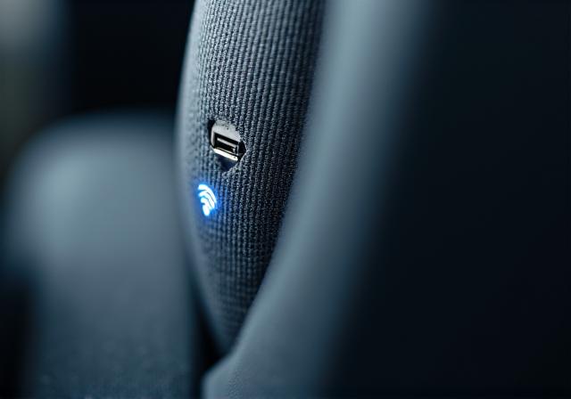 A close-up of a USB charging port and Wi-Fi symbol on a bus seat